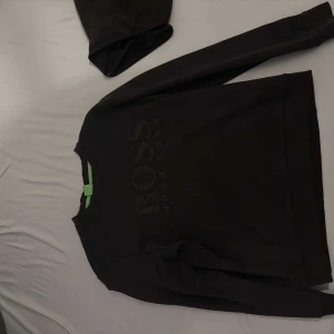 Svart och Grå tröja från Hugo Boss - 800kr för både tröjorna! Säljer en stilren grå och svart  tröja från Hugo Boss med diskret logga på framsidan. Tröjan har långa ärmar och en klassisk rund halsringning. Perfekt för en avslappnad och snygg look.