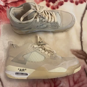 Jordan 4 off white - Snygga beige Nike Air sneakers med unik design och text på skosnörena. Skorna har en synlig luftdämpning i sulan och en stilren look. Perfekta för dig som vill ha något trendigt och bekvämt.
