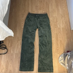 Gröna mjukisbyxor med fickor - Snygga gröna mjukisbyxor med bred resårmidja och snörning. Byxorna har praktiska fickor både fram och bak med knappdetaljer. Perfekta för en avslappnad stil.