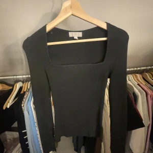Svart ribbad tröja från H&M - Säljer en stilren svart ribbad tröja från H&M. Tröjan har en fyrkantig urringning och långa ärmar. 
