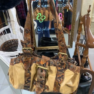 Beige och brun axelväska med ormmönster - Snygg axelväska i beige och brunt med coolt ormmönster. Väskan har breda axelremmar och detaljer som spännen och bälten i samma mönster. Perfekt för att ge din outfit en unik touch.