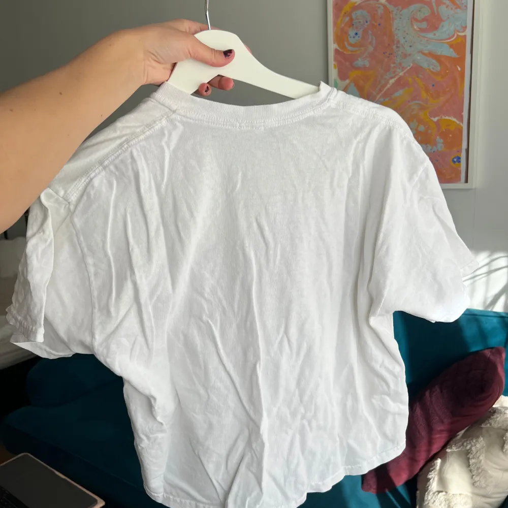 Säljer en vit t-shirt med tryck av röda rosor och texten 'Oxford 1991'. T-shirten har en croppad stil och korta ärmar, perfekt för en avslappnad look. Passar mellan xs-m, bra skick men lite skrynklig . T-paidat.