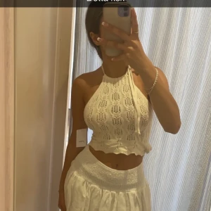 Vit virkad halterneck topp - Säljer en söt vit virkad halterneck topp med ett fint mönster och volangkant. Toppen är croppad och perfekt för varma sommardagar. Passar bra till både kjol och byxor. Perfekt för en dag på stranden eller en somrig utflykt! 🌞