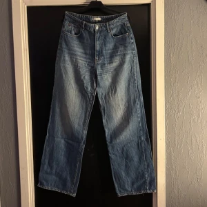 Blå jeans från Gina Tricot - Snygga blå jeans från Gina Tricot med klassisk femficksdesign och knappgylf. De har en avslappnad passform och raka ben, perfekta för en casual look. Passar bra till både sneakers och kängor.