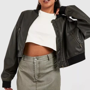 Svart bomberjacka i skinn - Snygg svart bomberjacka i skinn med dragkedja framtill. Jackan har en oversized passform och ribbade muddar vid ärmslut och nederkant. Perfekt för en cool och avslappnad stil.