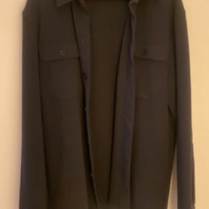 Svart overshirt från Only & Sons - Snygg svart overshirt från Only & Sons med knappar framtill och två bröstfickor med lock. Perfekt för lager-på-lager-stil. Tillverkad i ett robust material som ger en stilren look.