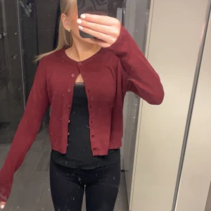 Vinröd kofta med knappar - Säljer en vinröd kofta med knappar framtill. Den har långa ärmar och nästan helt oanvänd 
