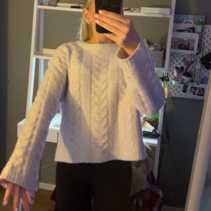 Vit stickad tröja - Säljer en mysig vit stickad tröja med flätmönster. Tröjan har långa ärmar och är väldigt gosig. Använd sparsamt 