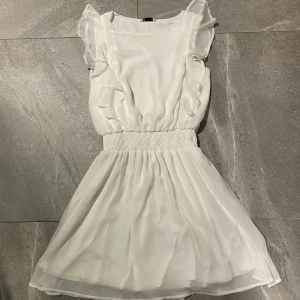 Vit klänning med volanger - Söt vit klänning med volanger och elastisk midja. Perfekt till studenten 🥰