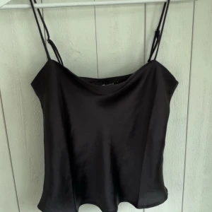 Svart satinlinne från Gina Tricot - Snyggt svart linne i satin från Gina Tricot med tunna axelband. 