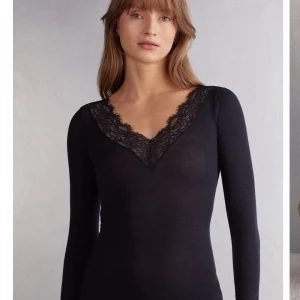 Svart tröja med spetsdetaljer ifrån intimissmi 💓💓 - Elegant svart långärmad topp med v-ringning och spetsdetaljer vid hals och ärmslut. Perfekt för en stilren look.