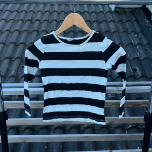Randig långärmad tröja från Lindex - Svartvit långärmad tröja från Lindex i storlek 128. Tröjan har breda horisontella ränder och är gjord i mjuk bomull. Perfekt för dig som gillar en klassisk och enkel stil med lite edge.