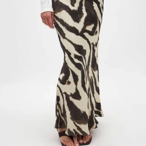 Zebramönstrad långkjol i satin - Lapp kvar!! Supersnygg långkjol med zebramönster i svart och beige. Kjolen har en lätt utsvängd passform och är gjord i ett glansigt satinliknande material som ger en lyxig känsla. Perfekt för dig som vill sticka ut med ett djurmönster.