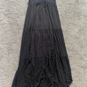 Svart långkjol med volanger - En svart långkjol med flera volanglager och bred resår i midjan. Passar till sneakers eller sandaler och är lätt att matcha med olika toppar.✨✨Kjolen är väldigt liten i storleken och känns mer som s eller xs