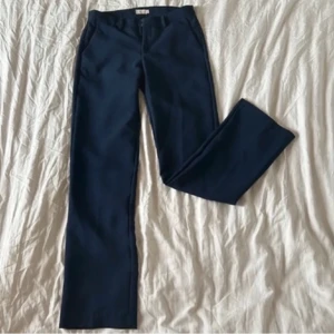 Lågmidjade kostymbyxor  - Marinblå lågmidjade kostymbyxor ifrån Nelly, innerbenslängd på ca 80-82cm. Jag är 160 och har haft de uppvikta de 2 gånger jag använt dem. Går annars att sy upp, passar någon som är ca 170-175.