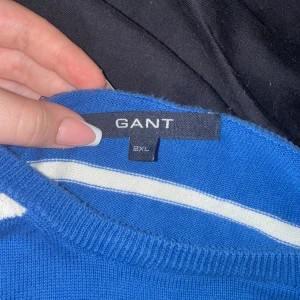 Blåvit randig tröja från GANT 2XL - Snygg blå tröja från GANT i storlek 2XL med vita horisontella ränder och broderad logga på bröstet. Klassisk rund halsringning och långa ärmar. Perfekt för dig som gillar preppy stil och vill ha något bekvämt och stilrent. Står 2xxl men passar som S