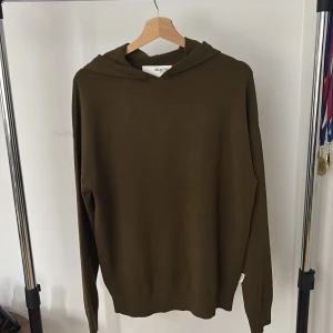 Olivgrön hoodie från Selected Homme - Snygg olivgrön hoodie från Selected Homme med klassisk huva och långa ärmar. Tröjan har en stilren och enkel design utan tryck eller mönster, perfekt för en avslappnad look. Tillverkad i mjuk bomull som känns skön mot huden.