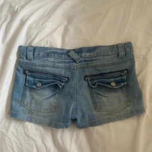 Lågmidjade jeansshorts i ljusblå denim - Snygga lågmidjade jeansshorts i ljusblå denim med klassisk femficksdesign och coola bakfickor med lock och knapp. Från neck&neck 🤍🤍 super fina❣️sitter som storlek S