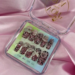 Y2K Rosa leopard (S);Medium Sqaure - Set med gelé press-on naglar i rosa leopardmönster, dekorerade med stora silvriga 3D-accessoarer som hjärta, rosett, stjärna och körsbär. Naglarna är medium och har en glansig finish med rosa fade, svarta och silvriga detaljer. Perfekt för dig som vill sticka ut med coola och glamorösa naglar. I storlek S: 15 mm, 11,5 mm, 12 mm, 11 mm, 9 mm 