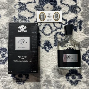 Creed Aventus - Lyxig Creed Aventus parfym på 100ml med ikonisk svart och silver design. Flaskan är genomskinlig med svart etikett och silverdetaljer, och kommer med originalkartong. Perfekt för dig som gillar exklusiva dofter och snygg förpackning.