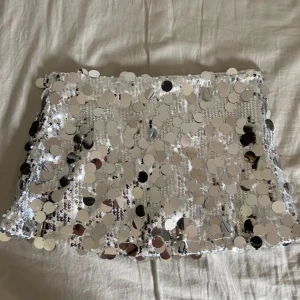 Snygg silvrig Paljettkjol stl S  - Supersnygg kjol som köpt utomlands, Perfekt för fester,konserter eller om du bara vill ge din outfit en snygg touch till! Mycketbraskick, det finns inbyggda byxor i vilket är perfekt!!  
