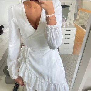 Vit omlottklänning från Bik Bok - Supersöt vit omlottklänning från Bik Bok med långa ärmar, v-ringning och volangdetalj nertill. Klänningen har knyt i midjan superfin och skön nu i sommar!!💞☀️(inte min bild på första!!) 