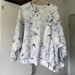 Vit och blå marmor-mönstrad sweatshirt - Säljer en oversized sweatshirt med unikt marmor-inspirerat mönster i vitt och blått. Tröjan har rund halsringning och långa ärmar, perfekt för dig som gillar en chill och trendig stil. Supermjuk och skön att bära till jeans eller leggings.