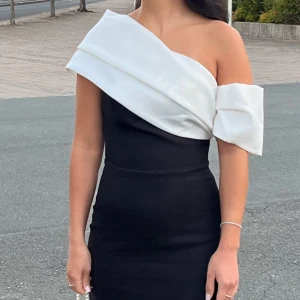 Svart långklänning med slits - Supersnygg svart långklänning med tight passform och hög slits framtill. Klänningen har en elegant och stilren look, perfekt för speciella tillfällen. Materialet känns mjukt och följsamt mot kroppen.