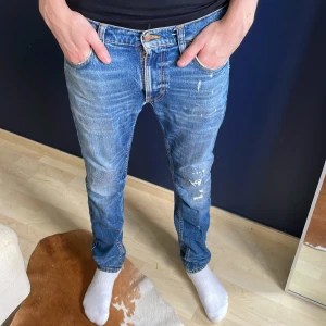 Blå jeans från Nudie Jeans - Säljer ett par klassiska blå jeans från Nudie. Modellen är Lean Dean och de har slitningar lite här o var.  Skick är typ 7/10 och de är i storlek 30/32. Kom dm ifall du vill ha fler bilder eller har någon fråga🤗