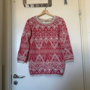Rosa och vit stickad tröja med mönster - Mysig stickad tröja i rosa och vitt med snyggt geometriskt mönster. Tröjan har lång ärm, rund hals med virkade detaljer och knytning i nacken. Perfekt för kalla dagar när du vill vara både varm och stilren. Från märket Odd Molly i storlek 1 som enligt deras storleksguide motsvarar en storlek S, men kanske passar en M. Mycket fint skick, jag hittar inga synlig anmärkningar eller defekter. 