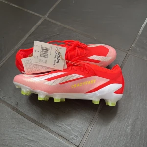 Adidas Crazyfast röda fotbollsskor - Snygga Adidas Crazyfast fotbollsskor i rött och rosa med vita detaljer och gula dobbar. Ovandelen är i syntetmaterial och har snörning för perfekt passform. HELT oanvända som ni ser på bilden❤️ nypris ca 3000