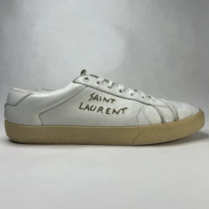 Saint Laurent Court classic SL/06 - Vita sneakers från Saint Laurent med handskriven logga på sidan. Skorna är i mjukt skinn med vita snören och beige sula. Klassisk låg modell med rund tå och diskreta sömmar. Tillverkade i Italien för en lyxig känsla. Skicket är bra, slitage på insidan finns vilket man inte ser, annars inga större defekter över huvudtaget . (⭐️Storlek 41 1/2 men passar 42). ✅Dustbag tillkommer.