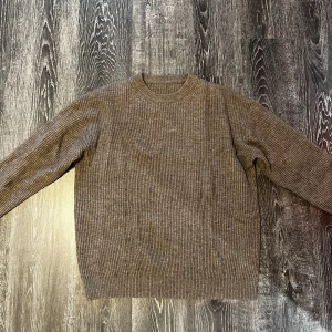 Brun ribbad stickad tröja från Muji - Mysig brun stickad tröja med ribbad struktur och rund hals. Perfekt för kyliga dagar och enkel att matcha med jeans eller kjol. Långärmad modell med avslappnad passform som ger en chill vibe.