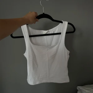 Vit linnetopp - Säljer en enkel och stilren vit linnetopp med breda axelband. Toppen har en rundad urringning och är tillverkad i mjuk bomull.