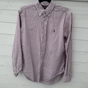 Ralph lauren skjorta - Ralph lauren skjorta som rosa randig i storlek S, väldigt bra skick och passar t allt, perfekt till sommaren. Säljer den för 499kr! Pris kan diskuteras!