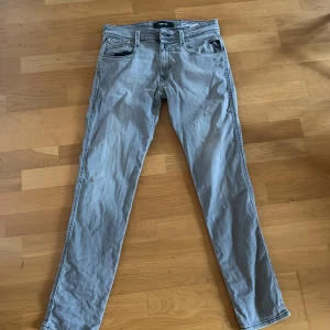 Grå Replay jeans anbass - Snygga grå jeans från Replay med klassisk femficksdesign och svarta kontrastsömmar. Jeansen har slim fit  passform och är tillverkade i mjukt denimtyg. Bakfickan har Replay-logga och cool broderad detalj. Jeansen är i storleken 31/32 och modellen anbass. välanvända utan några större tecken på användning därav det låga priset. Priset är inte hugget i sten och jag är villig att förhandla/gå ner i pris om man skulle köpa någonting annat från mig som en paket erbjudande 