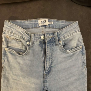 Ljusblå flare jeans från 157 - Snygga ljusblå jeans från 157 med klassisk femficksdesign och flare-ben. Jeansen har hög midja, dragkedja och knapp framtill. Perfekta för dig som gillar en retroinspirerad look med bekväm passform.