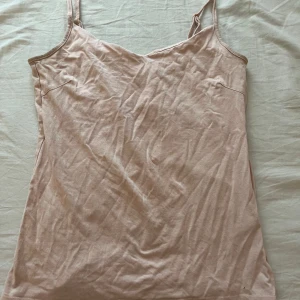 Beige linnetopp från 157, XS - Säljer en enkel och stilren beige linnetopp från 157 i storlek XS. Toppen har smala axelband med justerbar längd och är tillverkad i mjuk bomull med lite stretch för en skön passform. Perfekt att matcha med jeans eller kjol.