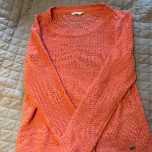 Korallfärgad stickad tröja från ONLY - Säljer en snygg korallfärgad stickad tröja från ONLY. Tröjan har rund halsringning och långa ärmar, perfekt för dig som gillar färg. Materialet är stickat och känns mjukt mot huden. Passar dig som vill ha en chill och enkel stil.