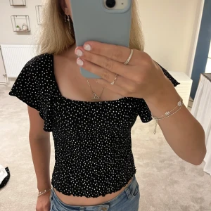 Svart prickig topp från Kappahl - Supersöt svart topp med vita prickar från Kappahl. Kan användas både offshoulder och som en vanlig topp! Super fint skick i storlek 170 