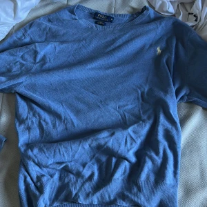 Blå tröja från Polo Ralph Lauren - Snygg blå tröja från Polo Ralph Lauren i slim fit med klassisk rund hals och diskret broderad logga på bröstet. Tillverkad i mjuk pima bomull som känns skön mot huden. Perfekt för dig som gillar stilrena och enkla plagg med premiumkänsla.