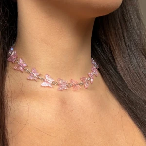 Egengjord halsband - Säljer en superfin choker med små rosa fjärilar som sitter på en tunn silverfärgad kedja som jag gjort själv! Halsbandet har justerbar längd.