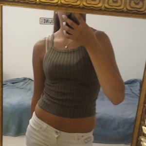 Ribbadt olivgrönt linne - Jätte sött ribbadt linne i olivgrönt med smala axelband och croppad passform. Materialet är mjukt och stretchigt, vilket gör den skön att ha på sig. Det är en lite liten storlek men det är väldigt stretchig så passar nog många. 💖