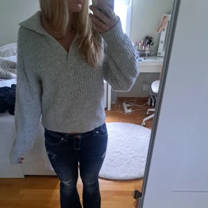 Grå stickad tröja med krage Gina Tricot - Supermysig ljusgrå stickad tröja från Gina Tricot med bred krage och v-ringad öppning. Tröjan har ett ribbat mönster och långa ärmar, perfekt för kyliga dagar. Passar dig som gillar en chill och snygg look.