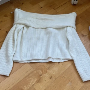 Offshoulder ribbad vit stickad tröja - Säljer en superfin offshoulder stickad tröja i ribbad modell. Tröjan är vit och har långa ärmar med bred krage som sitter snyggt över axlarna. Perfekt för dig som gillar en chill men ändå trendig look. Materialet är mjukt och värmande.