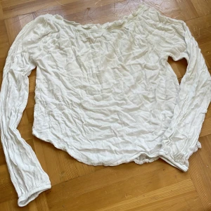 Vit offshoulder blus från Geology - Säljer en vit offshoulder blus från Geology med långa ärmar och broderad vinge-detalj vid halsen. Blusen är gjord i ett tunt och luftigt material, perfekt för vår och sommar. Elastiska muddar vid ärmslut ger en skön passform och en chill vibe.