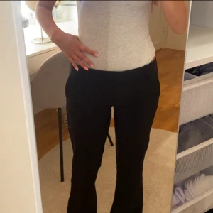 Svarta bootcut kostymbyxor - Snygga svarta kostymbyxor med bootcut passform som ger en schysst siluett. Byxorna har låg midja och klassisk design med fickor bak. Perfekta för dig som gillar stilrena och tidlösa plagg. Materialet känns mjukt och följsamt mot kroppen.