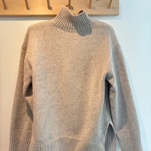 Beige polotröja i stickad ull XXS - Säljer en beige polotröja i stickad ull med ribbad hög krage och muddar. Tröjan har långärmade ärmar och en loose passform, perfekt för att hålla dig varm och snygg under kyliga dagar. Enkel och stilren design som funkar till många olika looks. Pris kan diskuteras vid snabb affär!