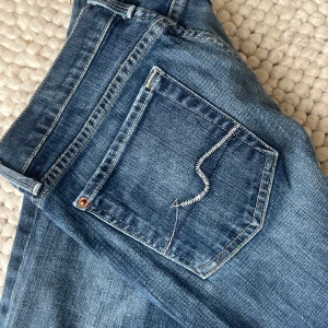 Blå jeans från 7 For All Mankind - Snygga lågmidjade blå jeans från 7 For All Mankind med klassisk femficksdesign och coola broderade detaljer på bakfickorna. Midjemått: 74