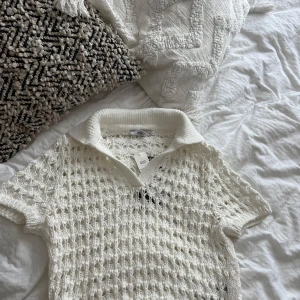 Vit stickad pikétröja från Xside - Säljer en vit stickad pikétröja från Xside i storlek S. Tröjan har korta ärmar, krage och ett luftigt hålmönster som ger en cool vibe. Perfekt för dig som gillar en chill och trendig stil. Materialet är mjukt och känns skönt mot huden. Prislappen är på. 